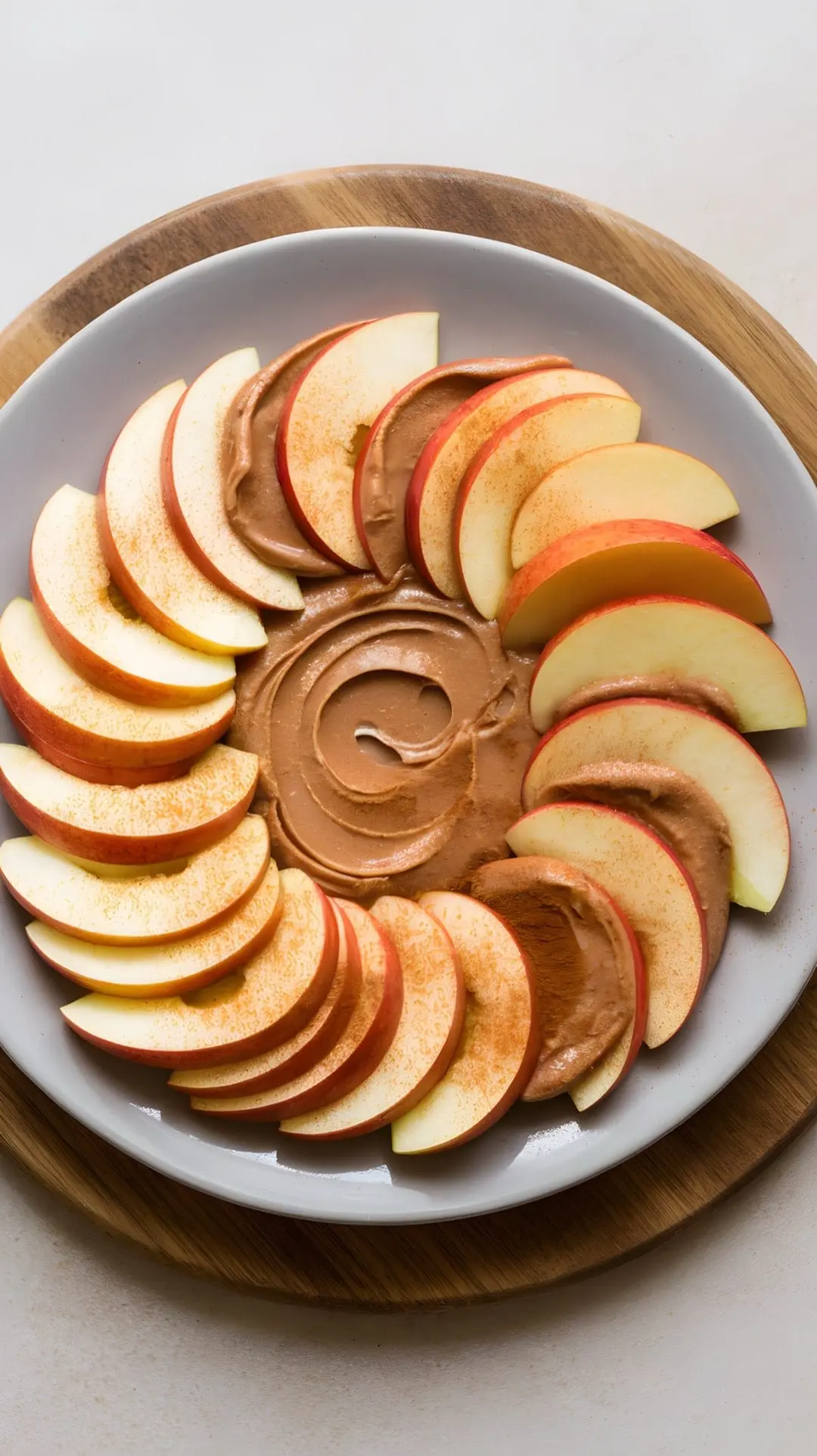 A plate of apple slices arranged around a swirl of nut butter.